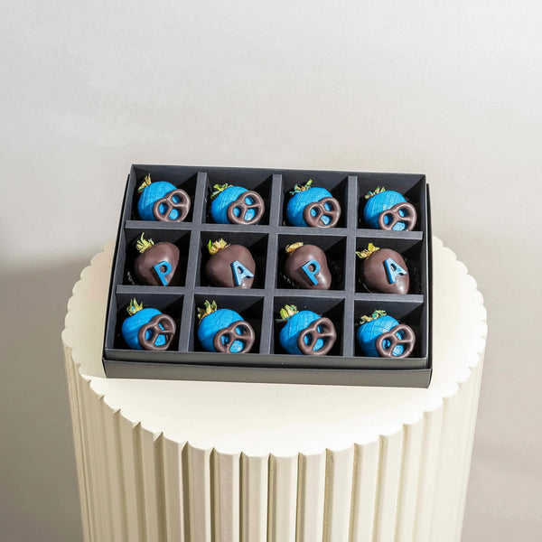 Box of assorted chocolates including blue and brown items on a white pedestal.